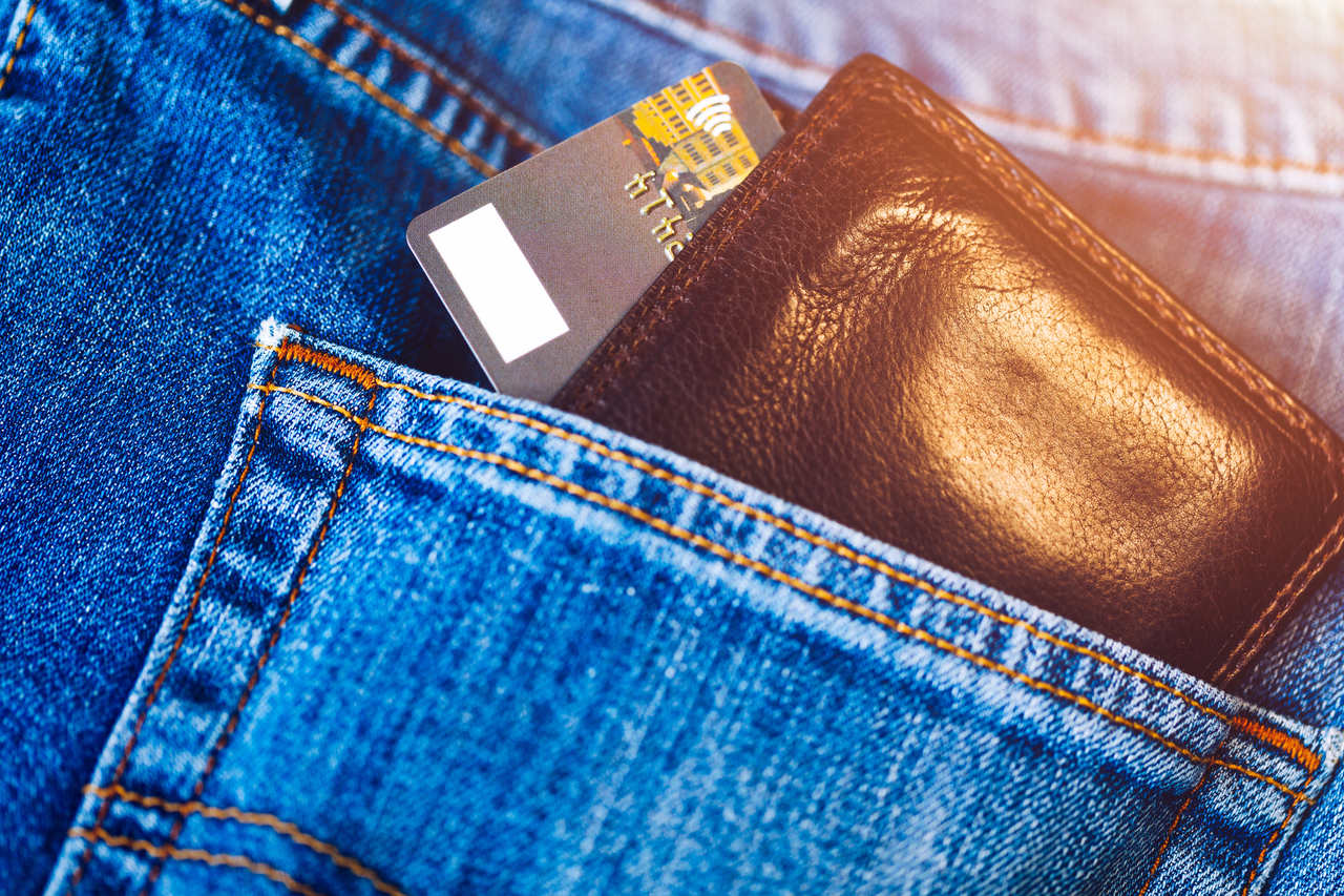 Karta płatnicza wystająca z portfela w kieszeniu dżinsów.